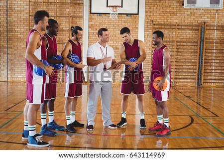 Coach interacting with basketball players in the court