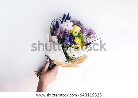  Bunch of anemone, yellow roses, narcissus  in woman's hand on white background