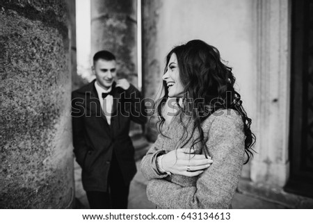 Romantic groom and beautiful bride posing near old columns