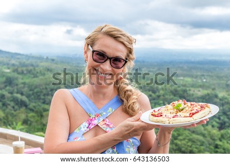 Woman with delicious strawberry pizza on a balinese tropical nature background. Bali island, Indonesia.