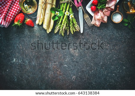 Fresh green and white asparagus with strawberries and wineglas on dark background Royalty-Free Stock Photo #643138384