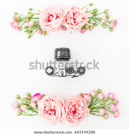 Old camera and roses, buds and leaves on white background. Flat lay, top view. Retro background.