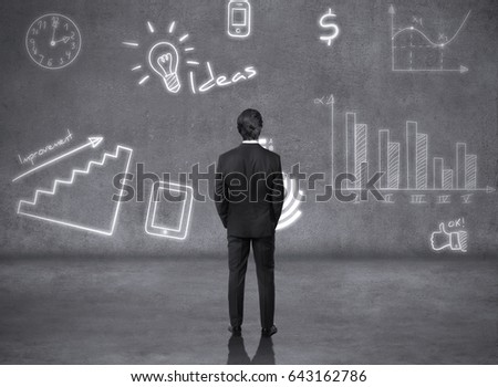 business man looking at sketches of graphs and symbols on the wall