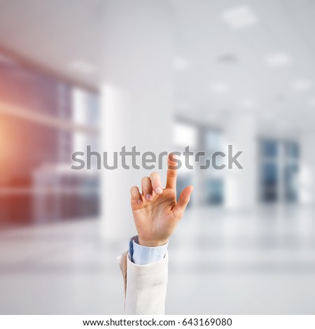 Close of businesswoman hand touching screen with finger and office at background