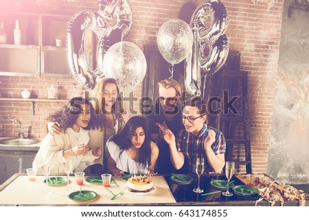 Young girl celebrates her birthday blowing out the candles with her friends,flare used to increase the mood and tones of composition