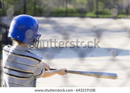 Young boy practicing hitting baseball at the batting cages for the first time, summer scene Royalty-Free Stock Photo #643219108