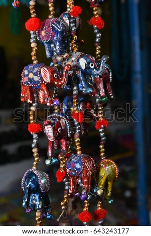 Display of colorful souvenir with small elephants displayed at shop in Udaipur, Rajasthan India. Antique Indian handicraft decorative elephant mirror work door hanging metal tapestry artificial beads Royalty-Free Stock Photo #643243177