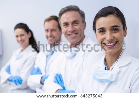 Portrait of smiling dentists standing with arms crossed in dental clinic Royalty-Free Stock Photo #643275043