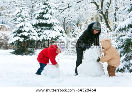 Happy family (mother with small boy and girl) in winter city park. Beautiful natural winter walking and playing with children concept.