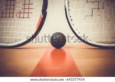 squash ball between two squash rackets on the court Royalty-Free Stock Photo #643377454