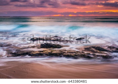 Dramatic rocks with fast moving waves at sunset, Sennen Cove, Cornwall, England