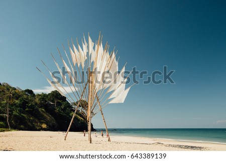 Bamboo decoration on background blue ocean shore and clear sky without clouds. Decorative figure bamboo on beach on background sandy coast and blue sea. Landscape sandy beach on seashore
