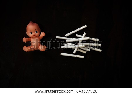 Cigarette put near baby doll, some cigarette put on table,that someone want to smoke ,Cigarette 's smoke very dangerous for lung and baby. In word have campaign  "world no tobacco day"  stop smoking.