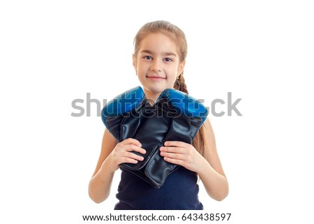 little smiling girl looking at the camera and holding a big boxing gloves