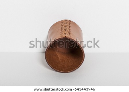 a leather cylinder for pencil on the grey background.