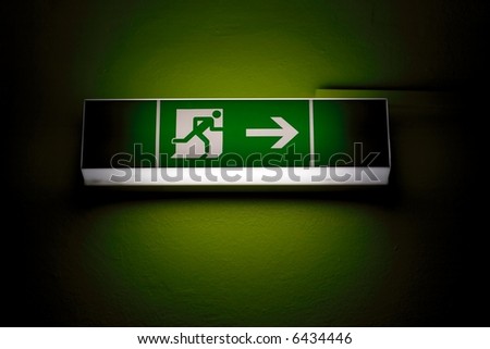 Emergency exit sign in a building glowing green Royalty-Free Stock Photo #6434446