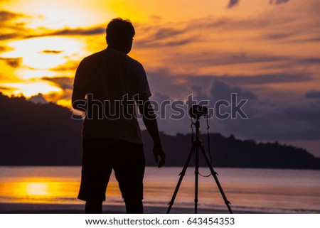 Silhouette photographer takes a picture at sunset on a tropical beach