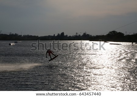 Wake Boarder Doing Half Somersault Creating Plume of Spray Backlit by Late Afternoon Sun in the Ski Rixen Area of Quiet Waters Park Lake, Deerfield Beach, Florida