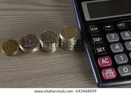 stack of coins and calculator on a wooden surface