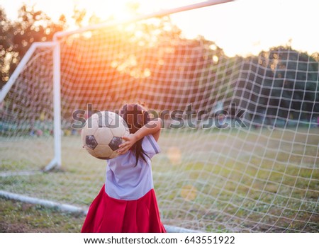 Close up picture of an old ball and foot of a girl who is playing football in the sunshine day.