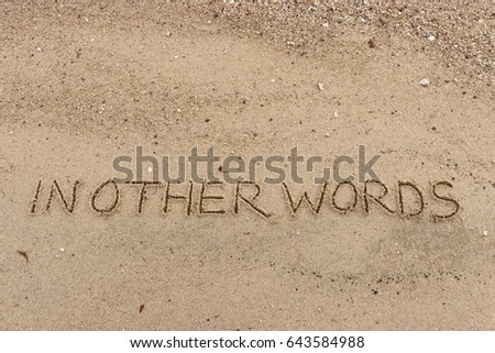 Handwriting  words "IN OTHER WORDS" on sand of beach. Royalty-Free Stock Photo #643584988