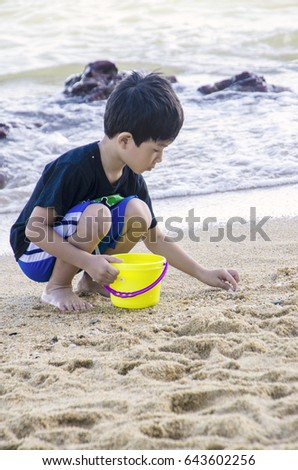 IMAGE OF A BOY PLAYING WITH SAND AT THE BEACH