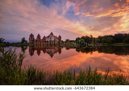 Mir, Belarus.Picturesque Summer View Of Mir Castle Complex On Sunny Sunset Sky Background And Glow Reflexions On Lake Water. Famous Landmark, Ancient Monument Under Morning Dramatic Sky.  