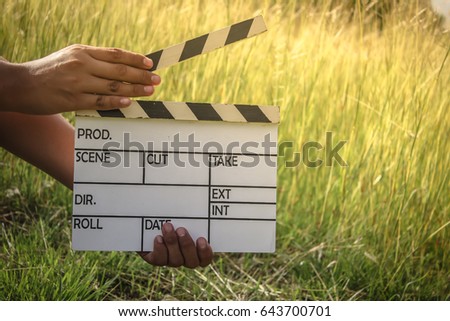 Hands hold a clapperboard or film slate in the meadow