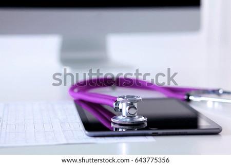 Tablet computer with a stethoscope lie on a table