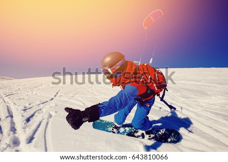 Snowboarder with a kite on fresh snow in the winter in the tundra of Russia against a clear blue sky. Teriberka, Kola Peninsula, Russia. Concept of winter sports snowkite. Royalty-Free Stock Photo #643810066