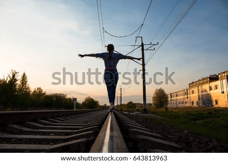 The girl is walking on rails