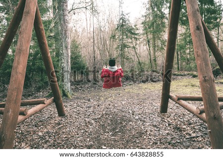 young woman in red dress using swings in spring forest having fun - vintage green look