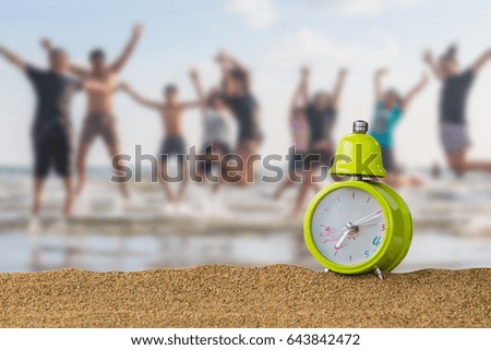 green clock on a sandy beach and blurry jumping of people  background 