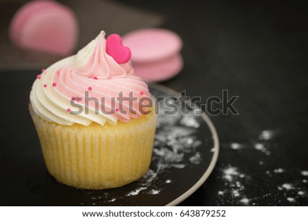 still life with pink cupcake on rustic dark background.