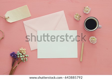 vintage mockup with flowers, cup of coffee and blank letter on pink wooden background