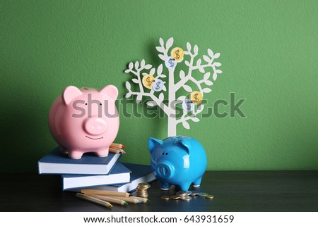 Piggy banks with stationery and money tree on green background