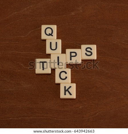 Crossword puzzle with words Quick Tips. Travel guide concept. Ivory tiles with capital letters on mahogany board.