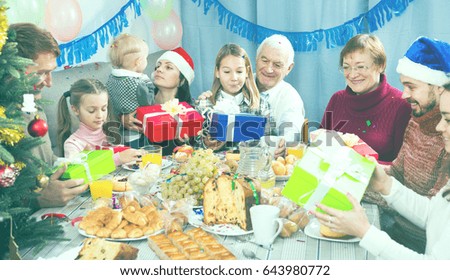 Large family handing gifts to each other during the Christmas dinner
