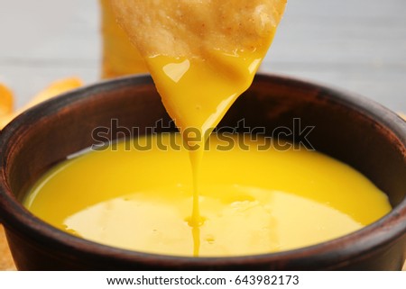 Dipping chips into bowl with creamy cheese sauce, close up Royalty-Free Stock Photo #643982173