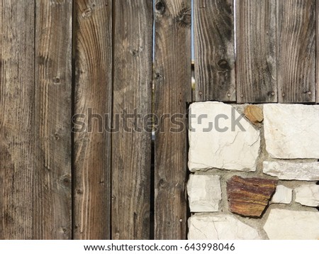 A stone wall that has been extended by a wooden fence