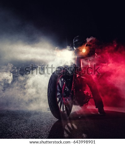 High power motorcycle chopper with man rider at night. Fog with backlights on background. Royalty-Free Stock Photo #643998901
