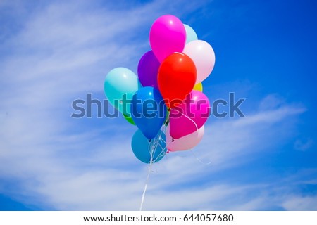 Beautiful holiday background.  Multicolored helium balloons flying in blue sky. 