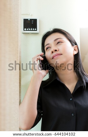 Portrait of happy young businesswoman talking on cell phone near office window