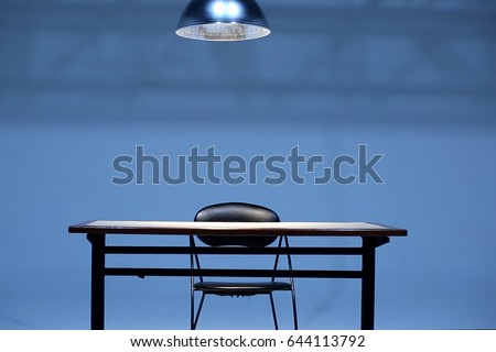 An empty Table and chair with hanging light bulb in room,  Investigation room concept Royalty-Free Stock Photo #644113792