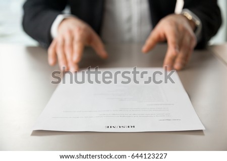 Resume document with guys hands in background. Recruitment manager reads resume. Job applicant offers CV to recruiter at interview. Employer examines achievements of new company worker. Close up photo Royalty-Free Stock Photo #644123227