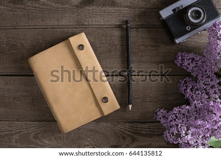 Lilac blossom on rustic wooden background with notebook for greeting message. Top view