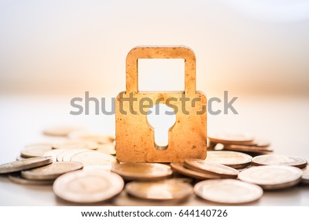 Money and Security Concept. Wooden master key lock icon on pile of coins.