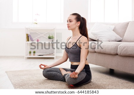Yoga at home, woman in meditation lotus pose. Young girl relax exercise