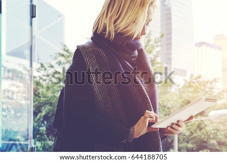 Woman tourist is searching in internet via touch pad a place where she could dine during travel in China. Female is chatting in social network via digital tablet, while is standing in business center