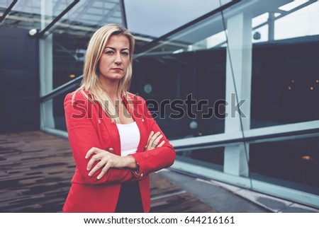 Portrait of successful business woman standing near office building. Confident female entrepreneur posing for the camera with crossed arms